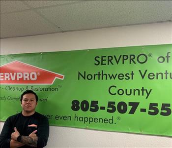 Male Employee Carlos standing in front of a SERVPRO banner