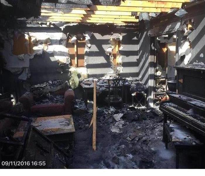 house fire damage showing exposed beams, burnt contents, and missing roof