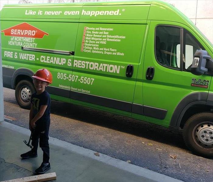 Cash posing for a photo in our workshop next to a SERVPRO van