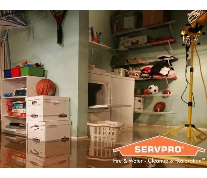 Shows a basement and laundry room, flooded with water. SERVPRO logo on the bottom right side