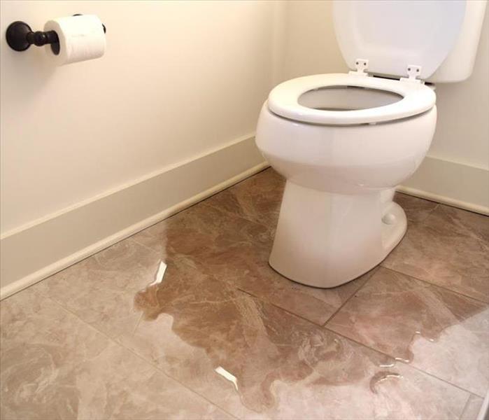 Toilet with water overflowing on tile floor