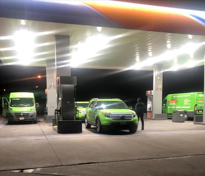 4 Servpro bright green vehicles at a gas station at night
