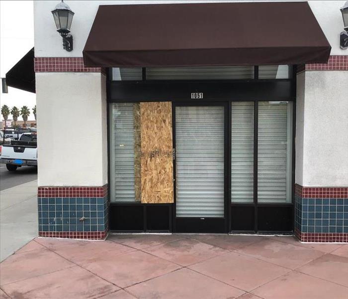 A small commercial building with a single window board up
