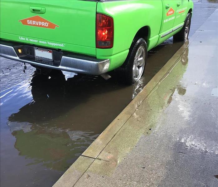 Green Servpro Ram Truck parked by curb showing gutter flooded with water