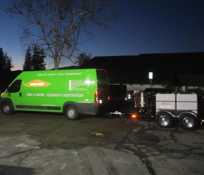Servpro Green van hauling a truck mount used to extract water