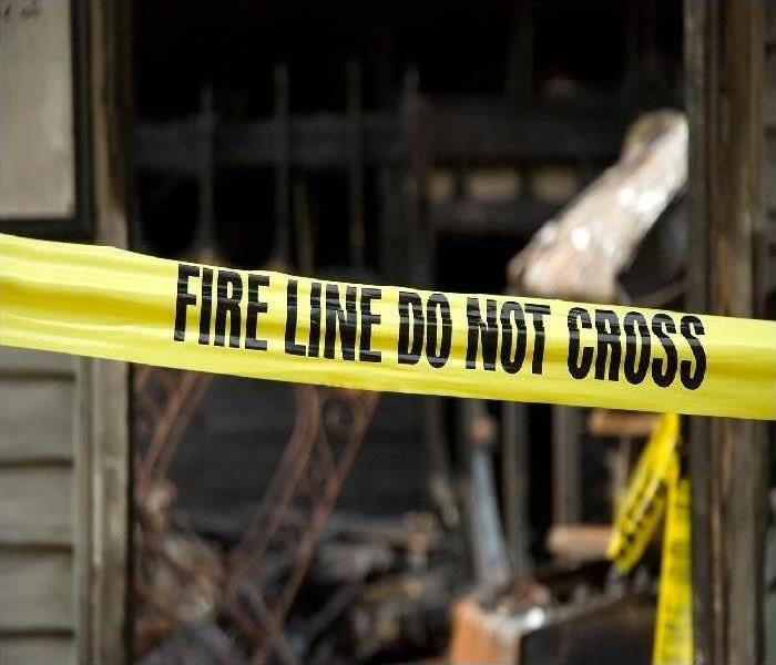 Burned home with  yellow tape across reading "Fire Line Do Not Cross"
